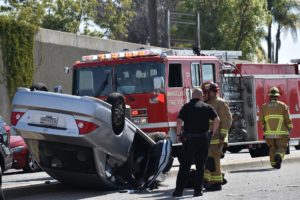 flipped car in auto accident with driver and firefighter nearby